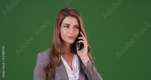 Pretty businesswoman talking on smartphone at work on green screen
