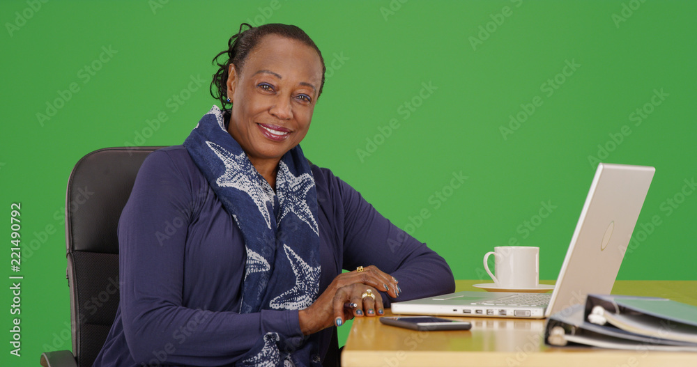 A black businesswoman poses for a portrait at her desk on green screen A black businesswoman poses for a portrait at her desk on green screen