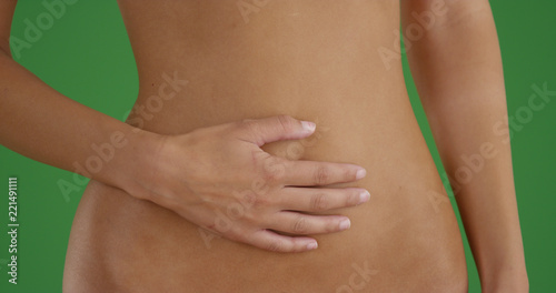 Closeup of slender woman's midsection as she rubs it on green screen