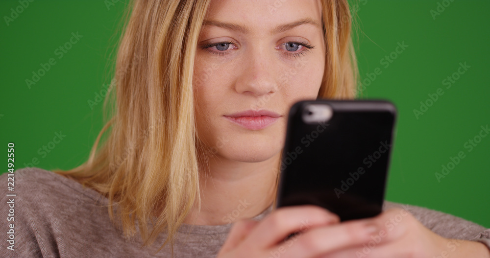 Millennial girl using cellular phone to send text messages on green screen Millennial girl using cellular phone to send text messages on green screen