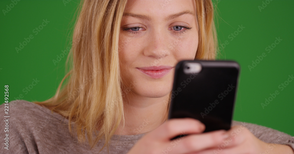 Pretty millennial girl using smartphone to send text messages on green screen Pretty millennial girl using smartphone to send text messages on green screen
