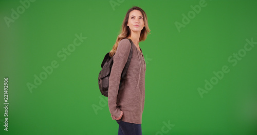 Attractive female wearing backpack looking around on green screen