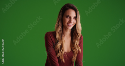 Female millennial sitting and smiling in contrasty lighting on green screen