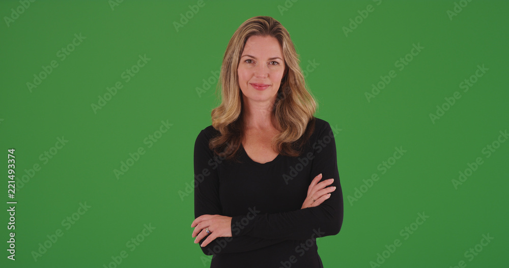 Attractive blonde female smiling at camera with arms crossed on green screen Attractive blonde female smiling at camera with arms crossed on green screen