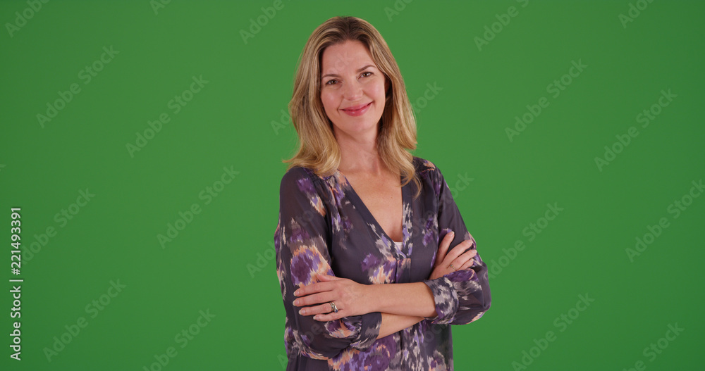 Caucasian woman with arms crossed smiling at camera on green screen Caucasian woman with arms crossed smiling at camera on green screen