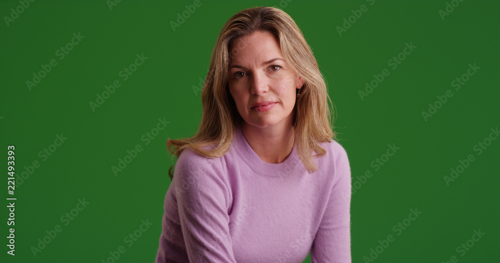 Blonde Caucasian woman wearing sweater looking at camera on green screen Blonde Caucasian woman wearing sweater looking at camera on green screen