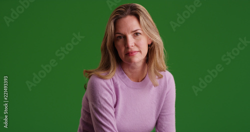 Blonde Caucasian woman wearing sweater looking at camera on green screen