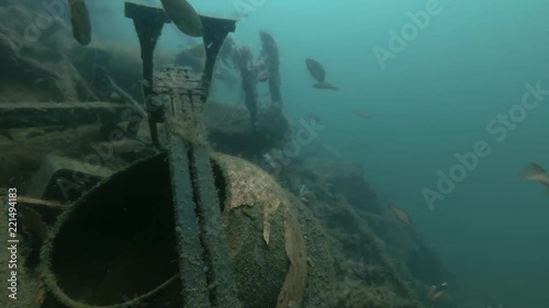 Garbage dump underwater in Norwegian Sea in the fjord. School of Cuckoo wrasse fish (Labrus mixtus) swim over dump
 photo