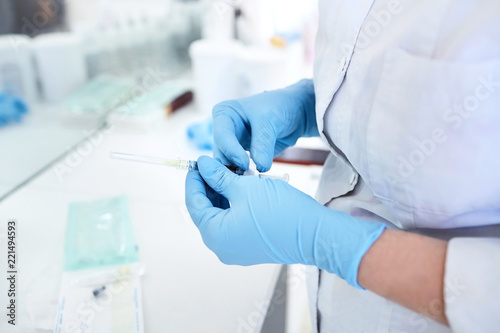 Hands of the beautician in blue gloves holding syringe. The cosmetologist prepares for a injection cosmetology procedure