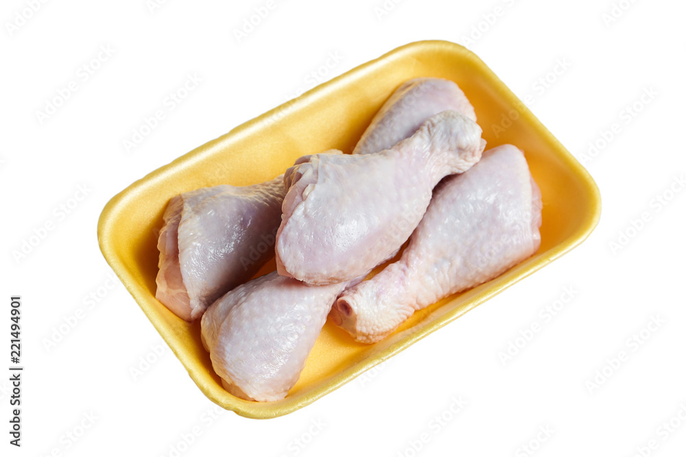 Raw and uncooked chicken legs with skin in a yellow plastic container. Fresh meat of poultry in tray, isolated on white background Raw and uncooked chicken legs with skin in a yellow plastic container. Fresh meat of poultry in tray, isolated on white background