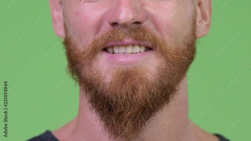 Close up shot of happy bearded man smiling against green background Close up shot of happy bearded man smiling against green background