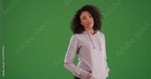 Young black female in gray hoodie with hands in pockets on green screen