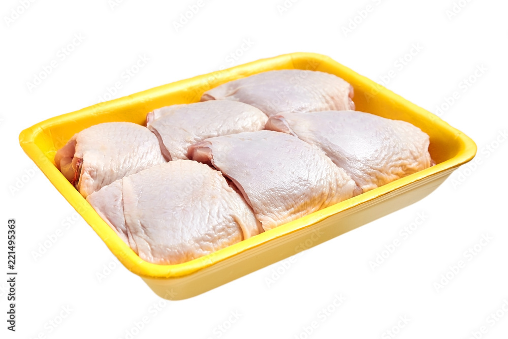 Raw and uncooked chicken thighs in a yellow plastic container. Meat of poultry in tray, isolated on white background Raw and uncooked chicken thighs in a yellow plastic container. Meat of poultry in tray, isolated on white background