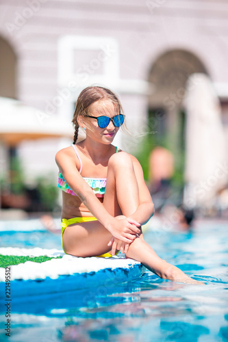 Beautiful little girl having fun near an outdoor pool
