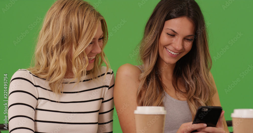 Couple of Caucasian girlfriends using smartphone together on green screen Couple of Caucasian girlfriends using smartphone together on green screen