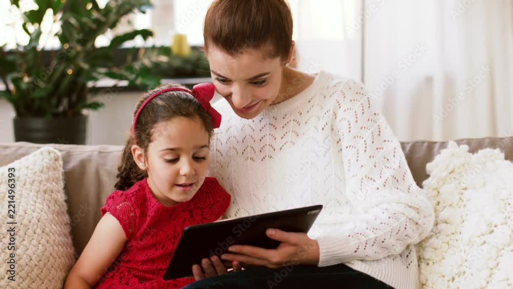christmas, technology and family concept - happy mother and daughter with tablet pc computer at home christmas, technology and family concept - happy mother and daughter with tablet pc computer at home