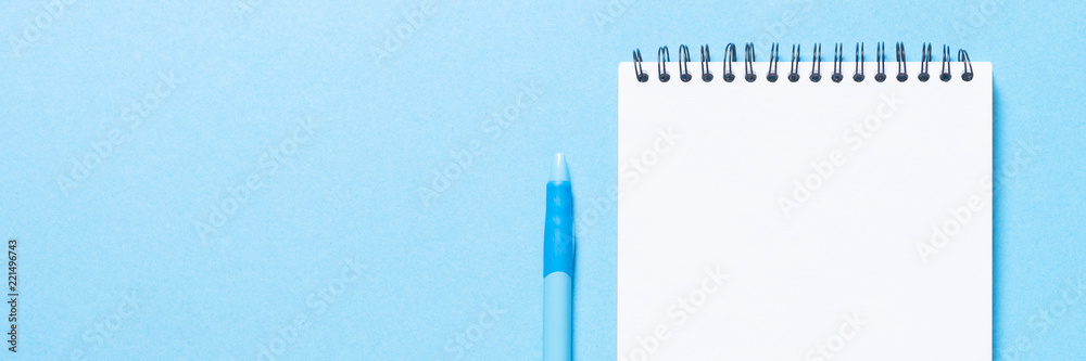 Notebook and pen on blue background.