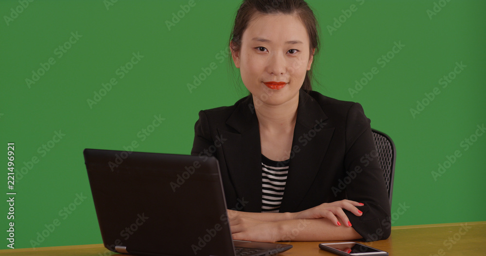 © Mark Adams - Successful Asian businesswoman sitting posing with laptop on green screen © Mark Adams - Successful Asian businesswoman sitting posing with laptop on green screen
