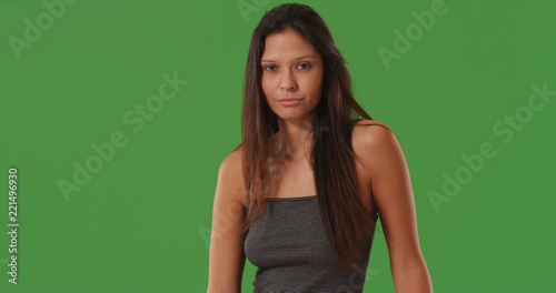 Pretty brunette female gazing at camera standing on green screen