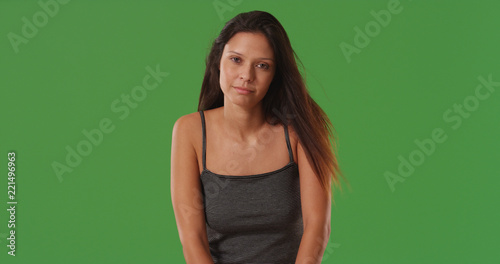 Somber attractive young millennial woman posing alone on green screen © rocketclips