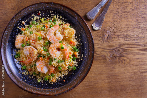 Shrimps with couscous, green peas, leeks and carrot. View from above, top studio shot