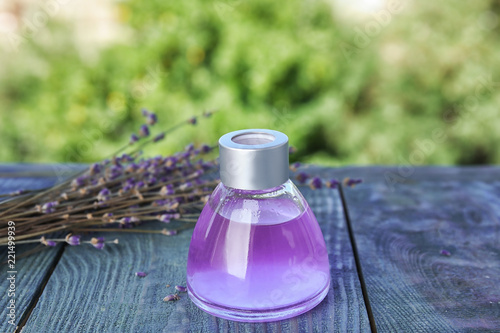 Fototapeta Naklejka Na Ścianę i Meble -  Natural herbal oil and lavender flowers on table against blurred background