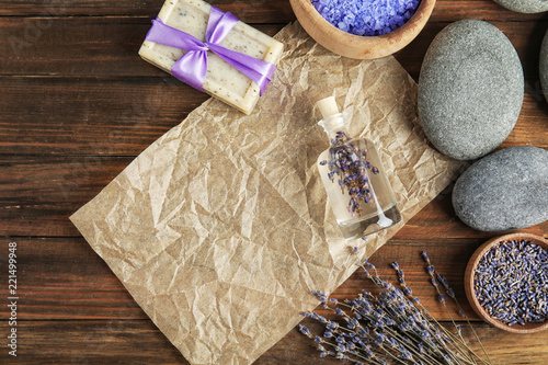 Fototapeta Naklejka Na Ścianę i Meble -  Flat lay composition with natural herbal oil, soap and lavender flowers on wooden background. Space for text