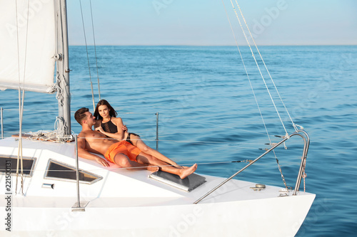 Young man and his beautiful girlfriend in bikini relaxing on yacht. Happy couple at sea