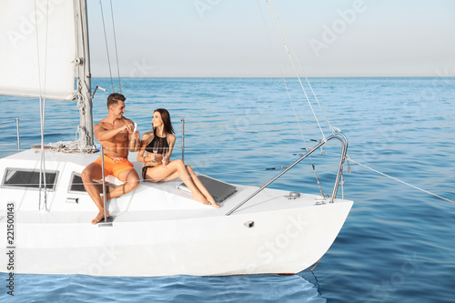 Young man and his girlfriend in bikini drinking champagne on yacht