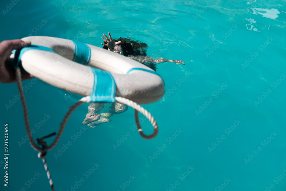 Life guard holding out life preserver to help young woman who is ...