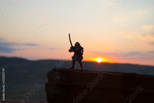 Fighter with a sword silhouette a sky ninja. Samurai on top of mountain with dark toned foggy background