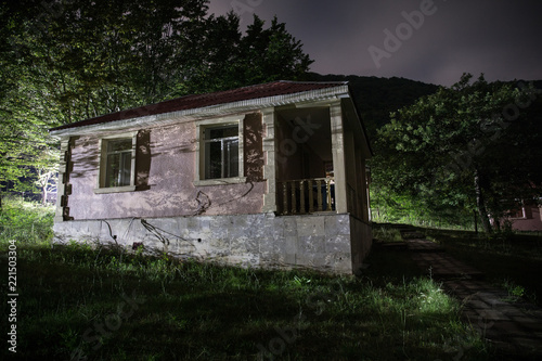 Mountain night landscape of building at forest at night with moon or vintage country house at night with clouds and stars. Summer night. © zef art