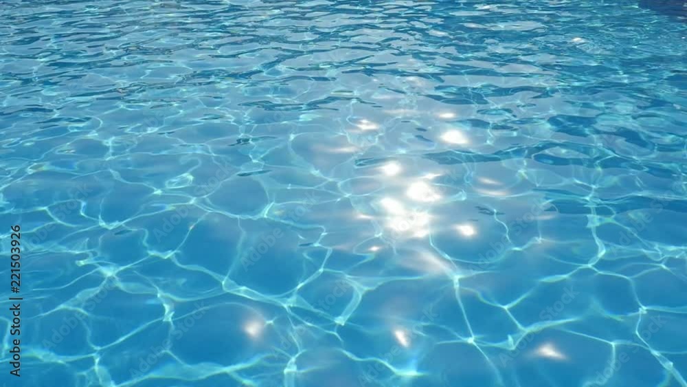 A beautiful view of sky blue waters in a swimming pool shot askew with a glittering network changing its shape in slow motion