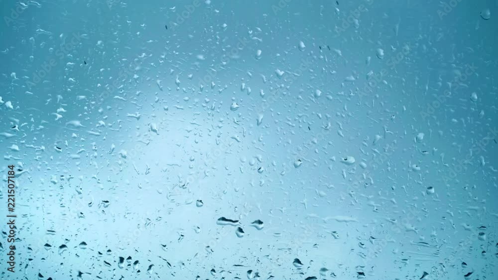 Close up view of water drops falling on glass. Rain running down on window. Rainy season, autumn. Raindrops trickle down, grey sky. Great for special effects and motion graphics Close up view of water drops falling on glass. Rain running down on window. Rainy season, autumn. Raindrops trickle down, grey sky. Great for special effects and motion graphics