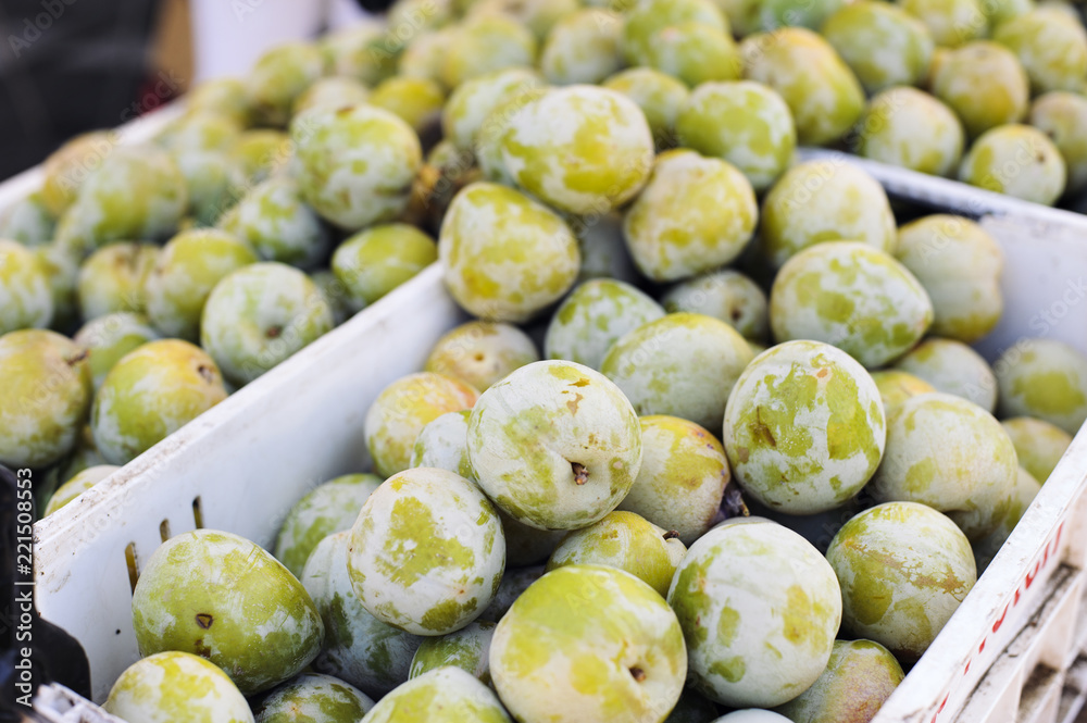 Boxes full of green plums at a stall in the farmers market Boxes full of green plums at a stall in the farmers market