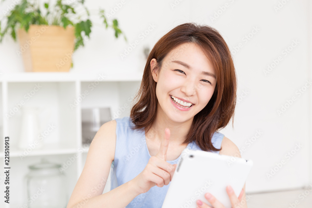 部屋でタブレットを見る女性