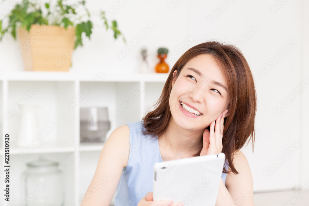 部屋でタブレットを見る女性