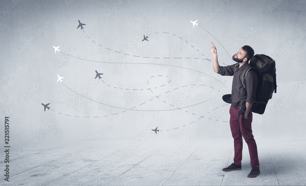 Handsome young man standing with a backpack on his back and little planes in the background