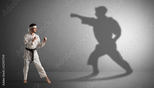 Young karate man confronting with his own shadow 