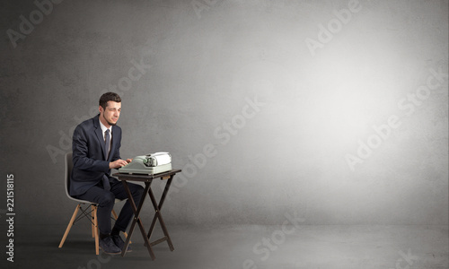 Man working hard on a typewriter in an empty space
 photo