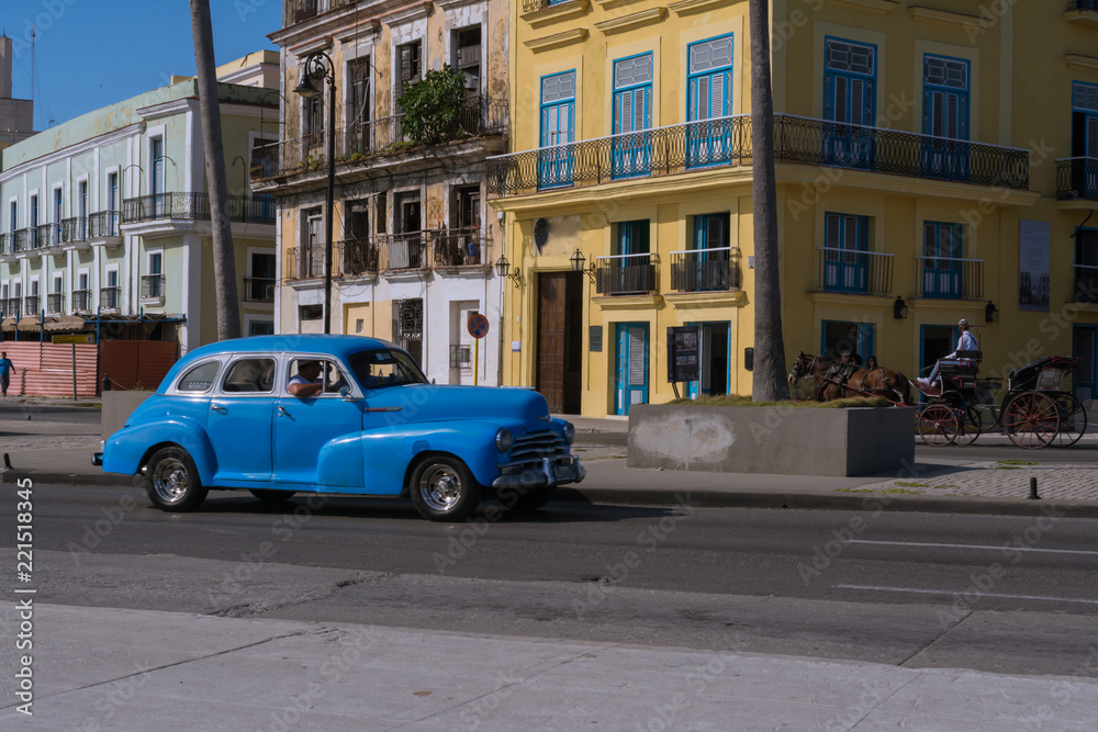 Un carro muy viejo de color azul realiza trabajo de taxi por  el casco histórico de la Habana.