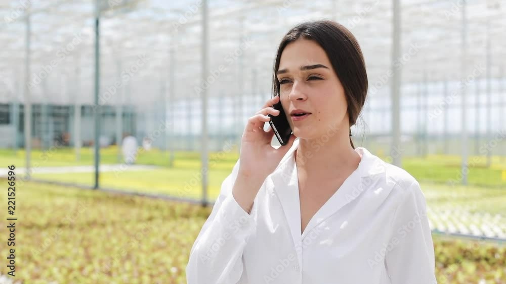 Worker walking in a greenhouse using mobile and talking on smartphone. Agricultural engineer working in greenhouse Worker walking in a greenhouse using mobile and talking on smartphone. Agricultural engineer working in greenhouse