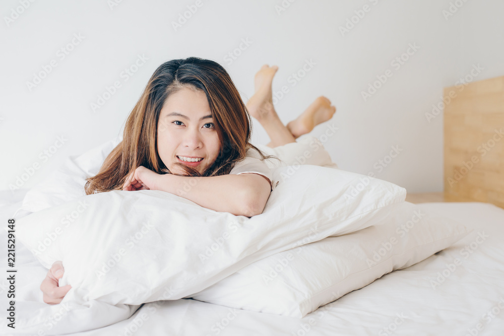 Happy Asian woman lying on bed with crossed legs and looking to camera. Happy Asian woman lying on bed with crossed legs and looking to camera.