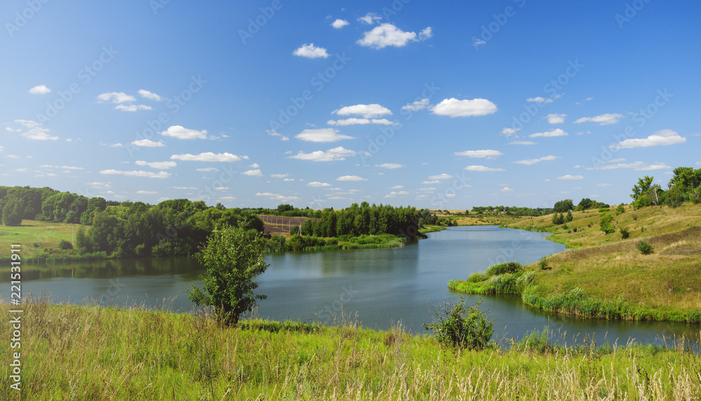 Sunny summer landscape with river,fields,green hills and beautiful clouds in blue sky.River Krasivaya in Tula region,Russia. Sunny summer landscape with river,fields,green hills and beautiful clouds in blue sky.River Krasivaya in Tula region,Russia.