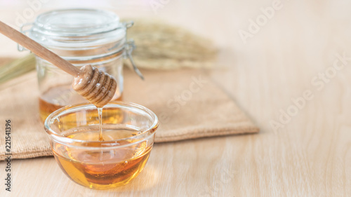 Honey in glass bowl and jar with dipper, healthy nutritional organic food from bee good for health, on wood table