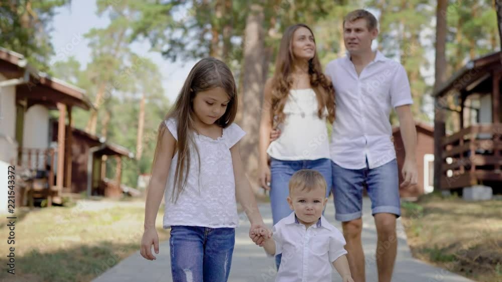 Happy male and female walking with children outside Happy male and female walking with children outside