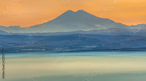 Mountains in the fog, haze. The Main Caucasian Range. Multicolored background. Mountains at sunset. Winter fog.
