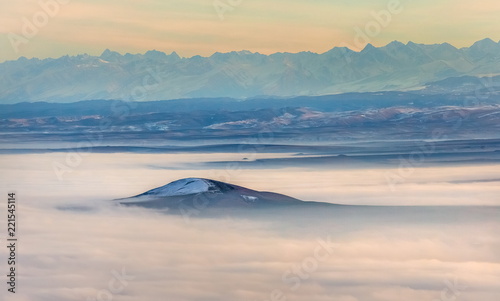 Mountains in the fog, haze. The Main Caucasian Range. Multicolored background. Mountains at sunset. Winter fog.