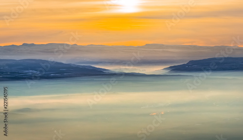 Mountains in the fog  haze. The Main Caucasian Range. Multicolored background. Mountains at sunset. Winter fog.