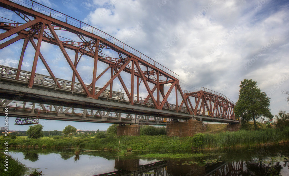 Railway bridge made of iron structures, against a cloudy sky background Railway bridge made of iron structures, against a cloudy sky background